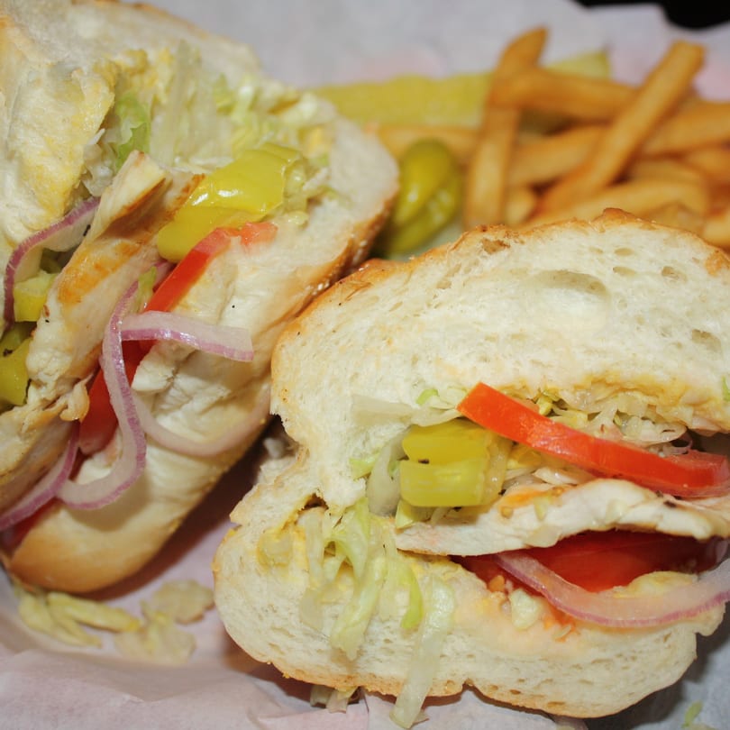 A Romano's Italian sub sandwich with chicken, lettuce, onions, and peppers, served with fries.